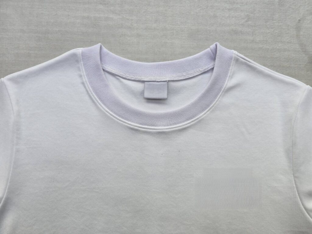 室内光源下で白いTシャツの首元リブ生地が身頃の白に対して青白く浮き上がって見えている色差の確認写真
